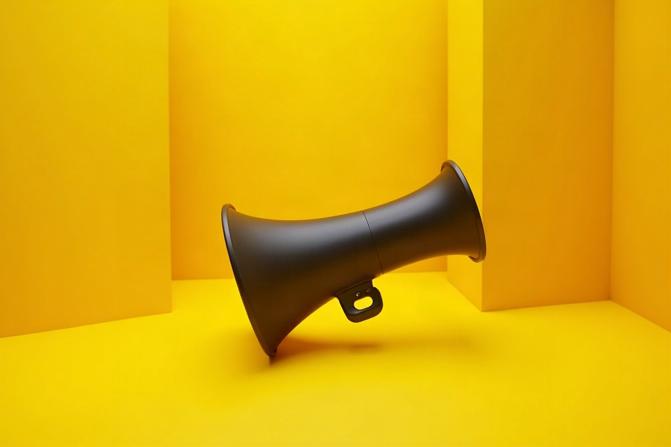 Mégaphone noir posé au sol dans un décor jaune